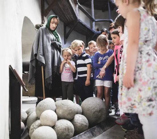 Kindergruppe auf historischer Museumsführung betrachtet Steinkanonenkugeln